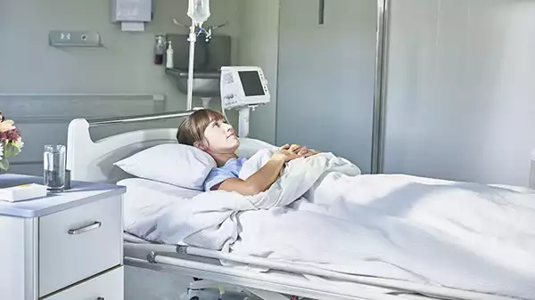 Sick woman in a hospital bed thinking about making a super insurance claim