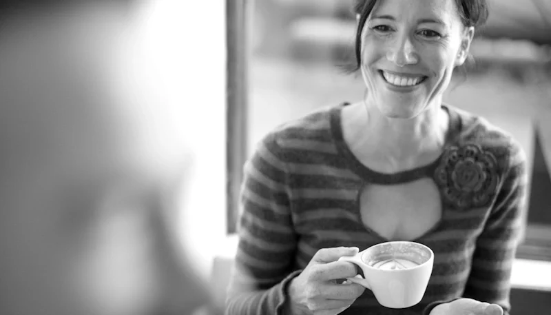 A smiling woman holding a cup of coffee after a successful psychological injury claim