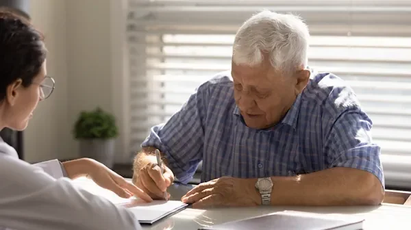 Photo of a sick man signing a critical illness claim form