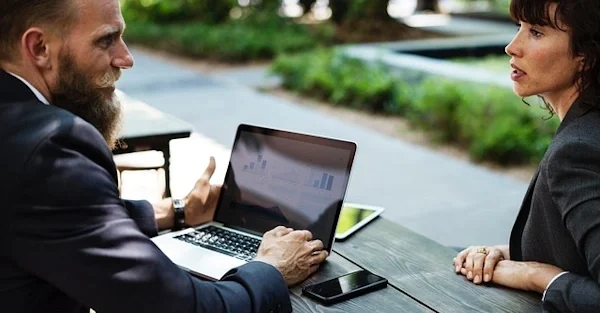 A lawyer meeting a client outdoors explaining super TPD policy requirements with a laptop